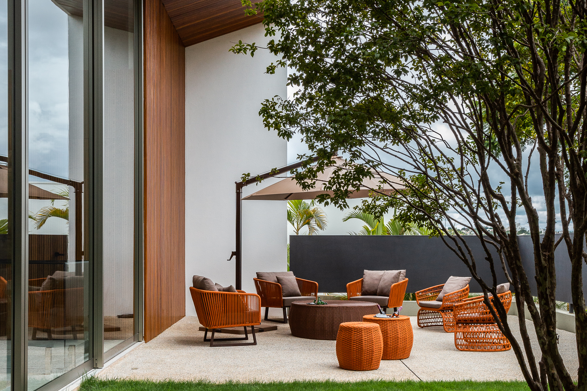 Casa 442 - Terraço coberto com mobiliário em fibra terracota, árvore integrada e vista para área externa