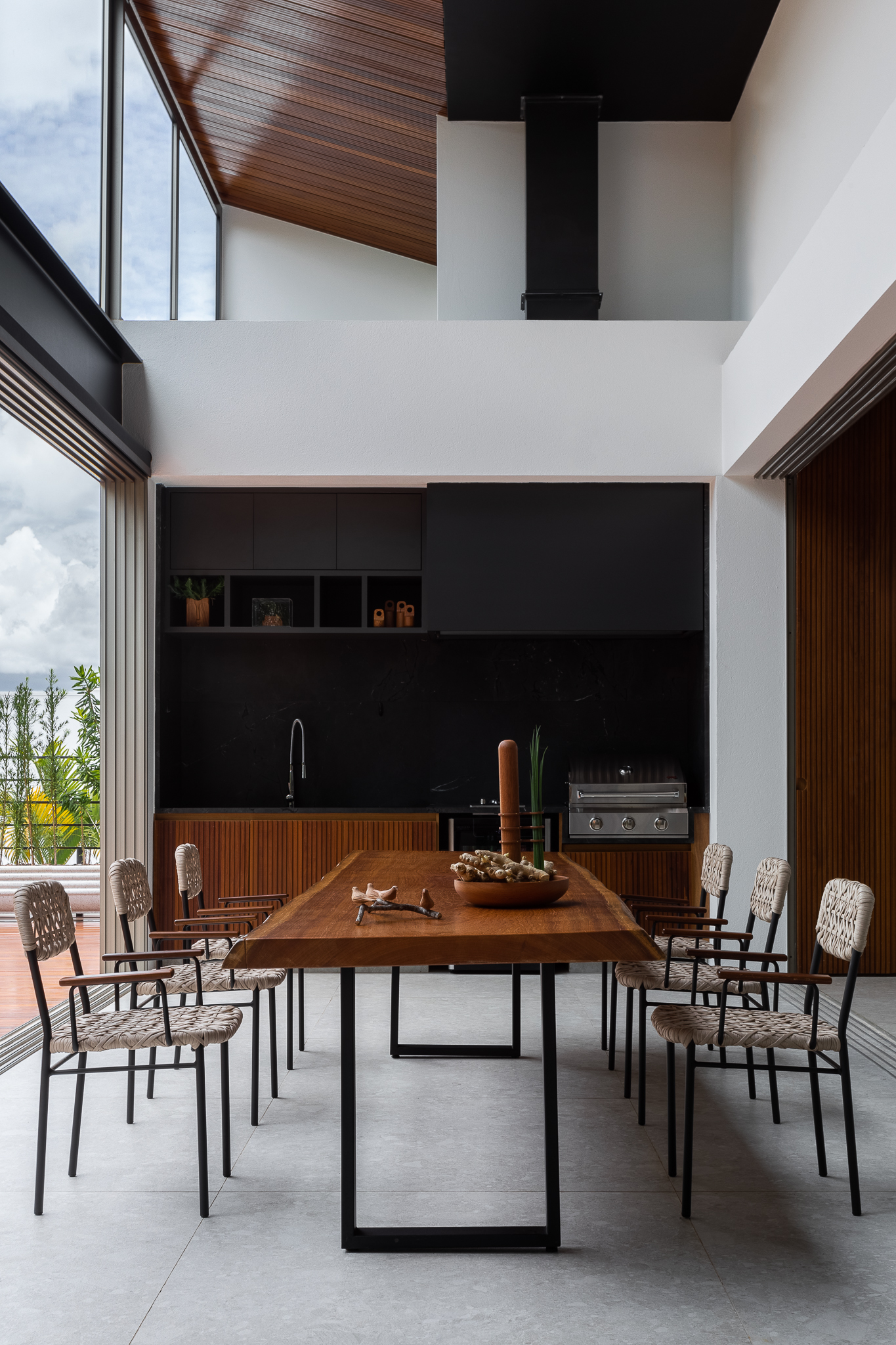 Casa 442 - Área de jantar com pé-direito duplo, mesa de madeira maciça e cadeiras em fibra natural