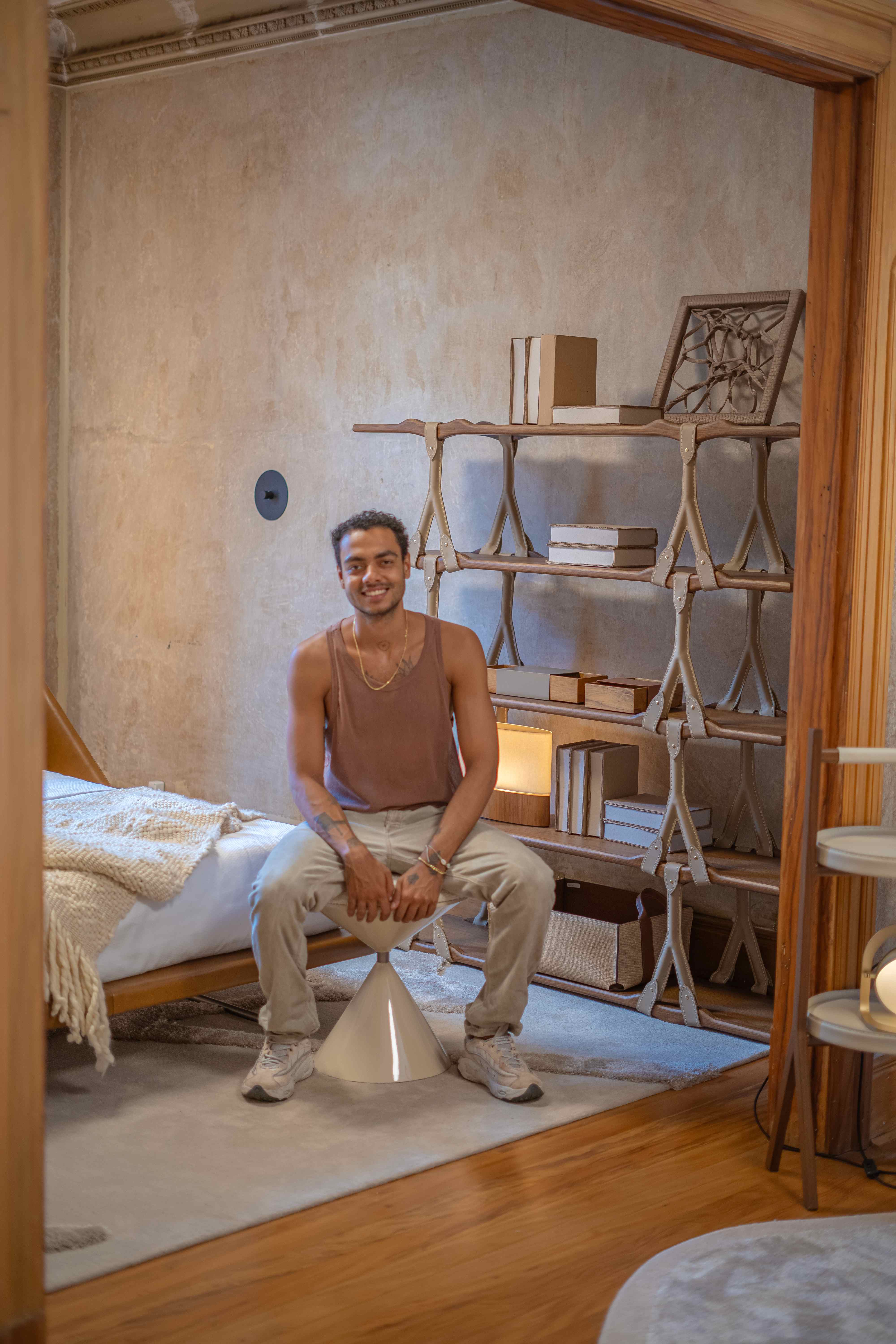 Caio Ferreira com estante modular e obras