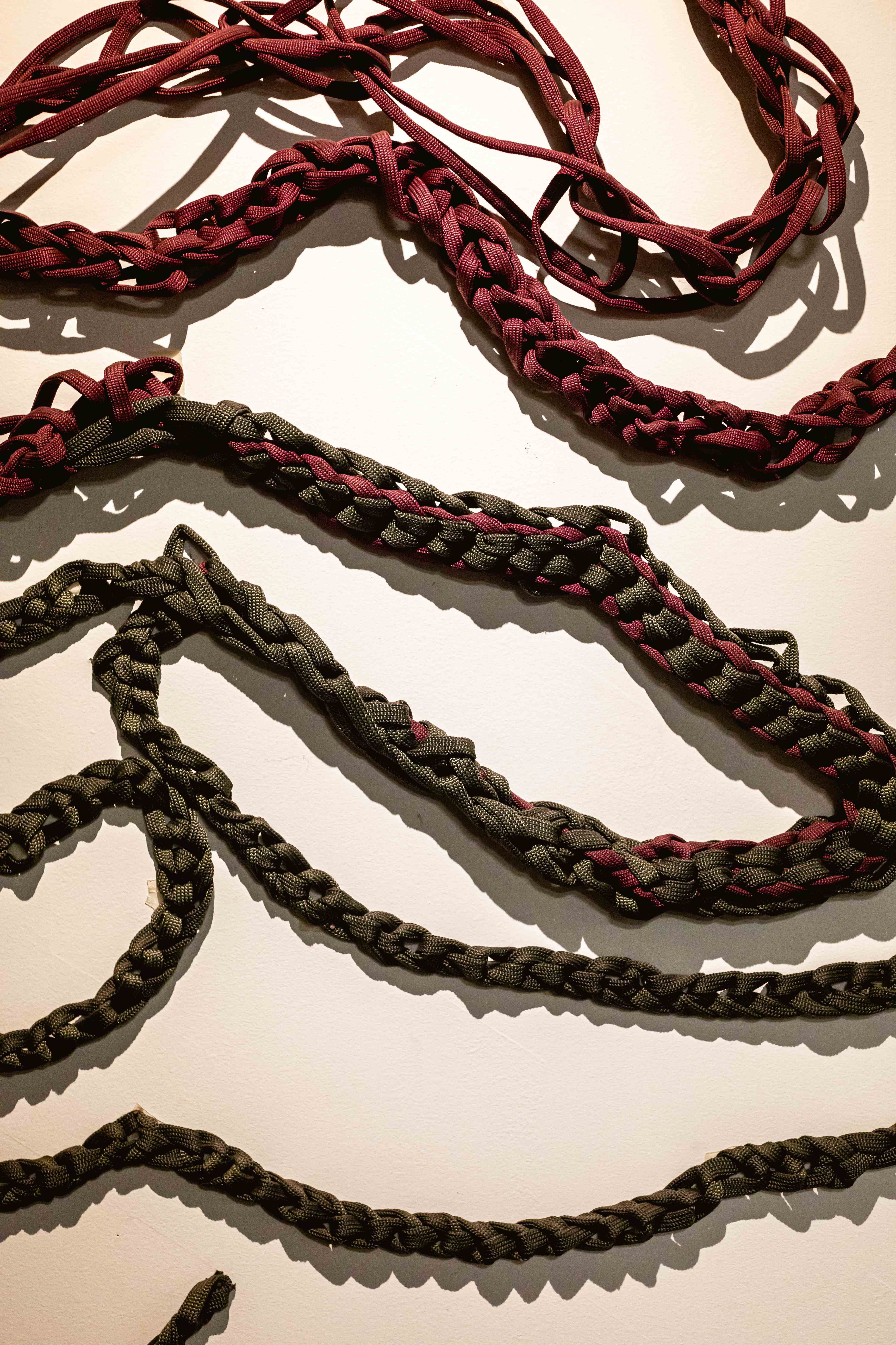 Detalhe das cordas trançadas mostrando a textura e construção das esculturas em burgundy e verde oliva